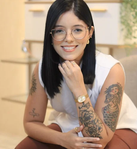Andressa Meneses sentada e sorrindo, em retrato próximo
